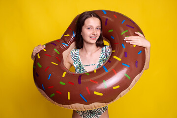 swimming trainer teen girl holding inflatable ring on yellow studio background