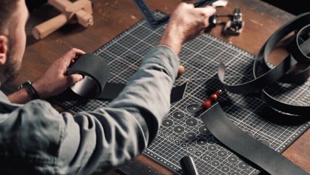 Leatherworker tanner draws, measures with ruler. Tanner works with leather, small business, production.