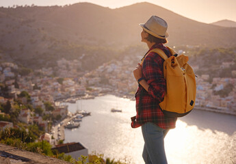 Nice asian Happy Female with backpack Enjoying her holidays on Symi Islands in sunset time. View of...