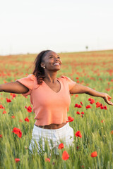 Naklejka na ściany i meble Happy ethnic woman standing on field of poppies