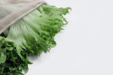 Raw lettuce from local market in reusable shopping bag over light background. Copy space. Top view. Organic food, edible fresh picked. Plastic Pollution, Ethical Consumerism, Healthy Eating concept