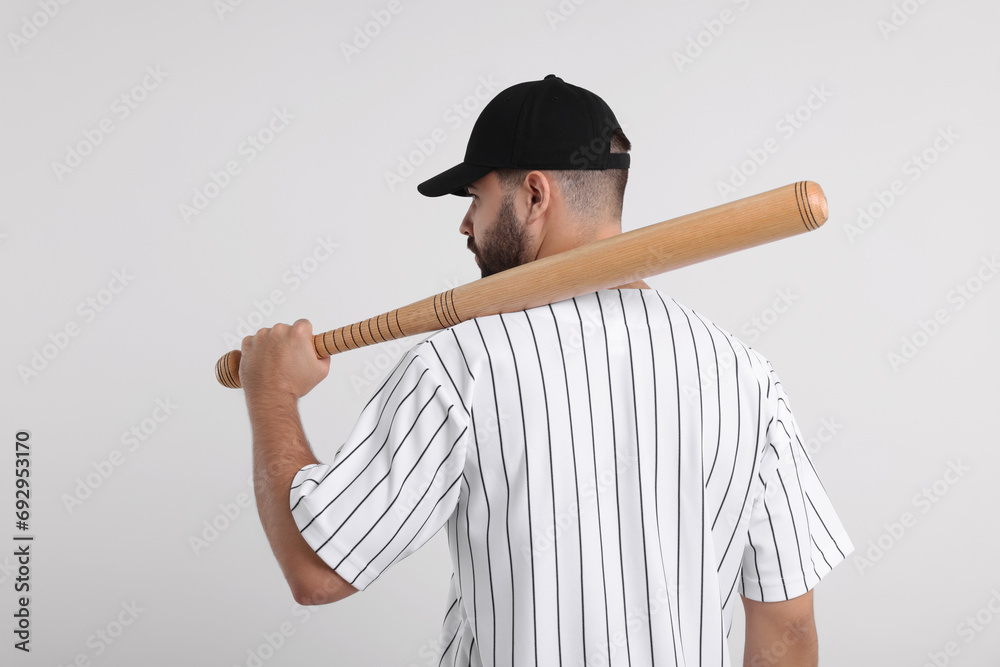 Wall mural Man in stylish black baseball cap holding bat on white background, back view