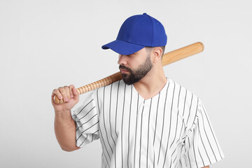 Man in stylish blue baseball cap holding bat on white background