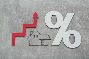 Mortgage rate rising illustrated by upward arrow, house icon and percent sign on gray background,...