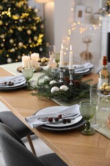 Christmas table setting with festive decor and dishware in room