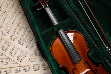 Violin, bow in case and music sheets on table, top view