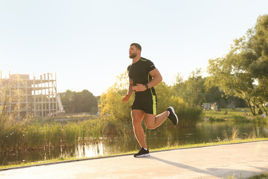 Young man running near pond in park
