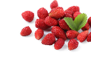 Ripe wild strawberries and green leaves isolated on white