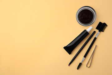 Flat lay composition with eyebrow henna and tools on beige background. Space for text