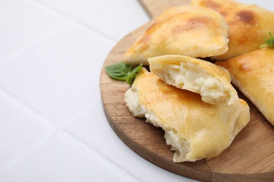 Delicious samosas and basil on white tiled table, closeup. Space for text