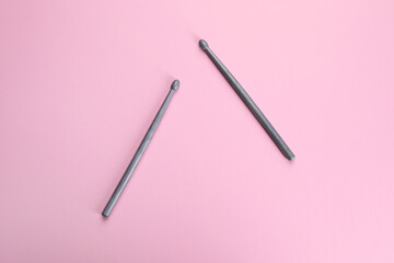 Two grey drumsticks on pink background, top view