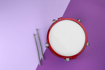 Children's drum with drumsticks on color background, top view. Space for text