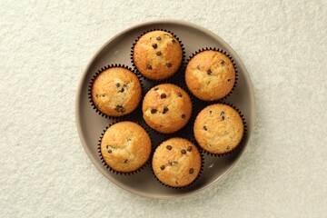 Delicious sweet muffins with chocolate chips on light textured table, top view