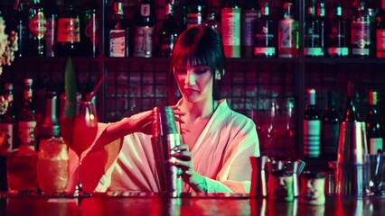 Focus on shakers. Young pretty woman working in pub, making delicious cocktails, mixing ingredients in shaker. Concept of occupation, nightlife, bar, party, alcohol drink, mixologist