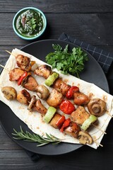Delicious shish kebabs with vegetables served on black wooden table, flat lay