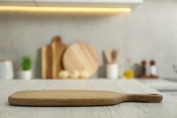 Wooden cutting board on white table in kitchen. Space for text