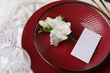 Stylish table setting. Dishes, glasses, blank card and flower, above view