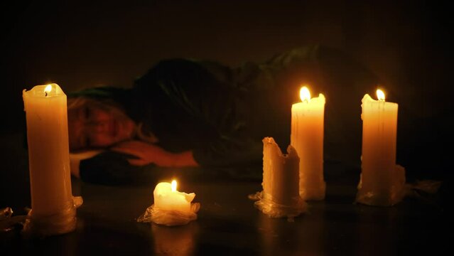 Beauty fantasy woman lying on floor sleeping surrounded by burning candles fire light in dark royal room full. Vintage old style black dress. Sexy gir dream. lady vampire in night castle art video 4k