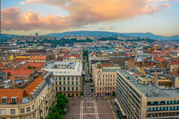 An aerial panoramic view from St. Stephen Basilica of Budapest, capturing Zrinyi street perspective, rooftops of Pest, and the hills of Buda with Buda Castle and Fisherman Bastion in the background