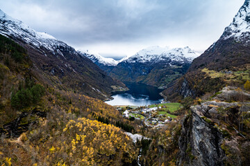 view on geiranger village from Flydalsjuvet viewpoint with Geirangerfjorden and mountains covered with snow on background