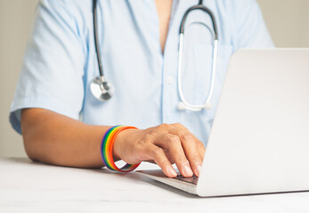 Doctor with a rainbow wristband in a hand while sitting at a desk in the hospital