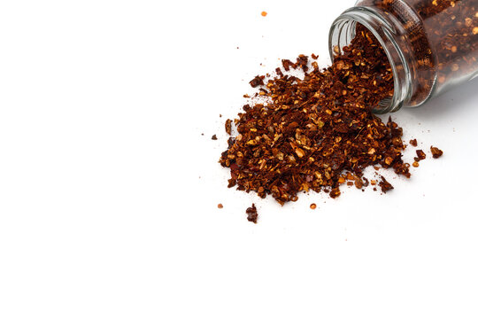 dried chili flakes spill out of glass spice jar, spice catalog concept