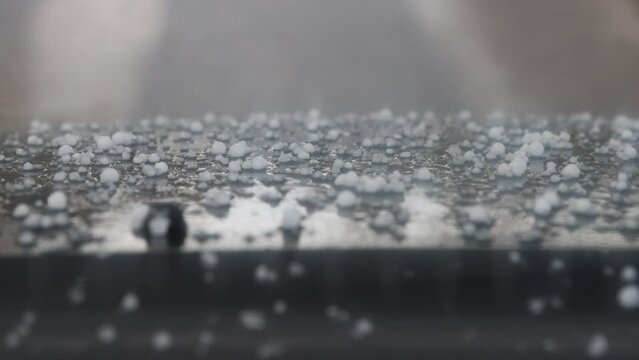 Hail and rain in late autumn. Bad weather on the field road. Hail was beating on the roof, and pounding on the windshield of the car and the windshield wipes are working