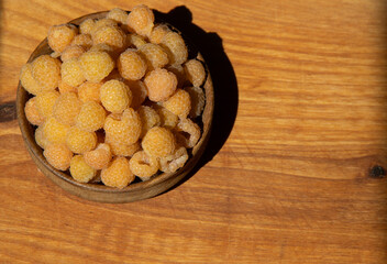 Yellow raspberries in a wooden bowl on the table. Summer berries background. Vitamin food, berry harvest. Healthy nutrition.