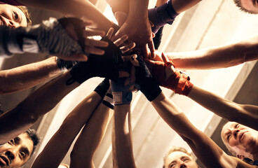 People smiling with their hands in a huddle in a boxing gym