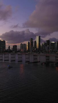 Miami at Evening Twilight. City Downtown and Rickenbacker Causeway. Blue Hour. Urban Cityscape. Aerial View. Florida, USA. Drone Flies Forward and Upwards. Vertical Video