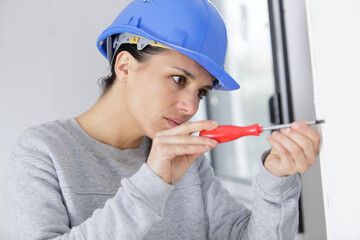 young woman drilling screws into plasterboard with a screwdriver