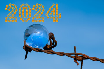 The concept of symbolism. On a blue sky is a glass globe, which is surrounded by rusty barbed wire...
