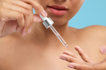 Woman applying serum onto her finger, closeup