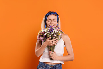 Happy hippie woman with bouquet of flowers on orange background