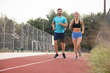 Obraz premium Healthy lifestyle. Happy sporty couple running at stadium, space for text