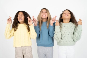 multi racial group of girl friends gesturing finger crossed smiling with hope and eyes closed. Luck and superstitious concept.