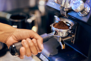 A female barista making a coffee using a professional coffee maker.