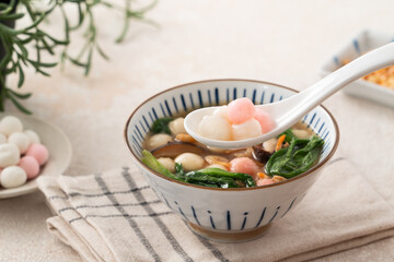 Eating red and white small tangyuan with savory soup and vegetable.