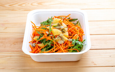 Carrot salad with orange. Healthly food. Takeaway food. On a wooden background.