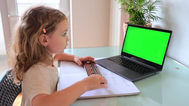 A girl from the back is engaged in mental arithmetic on the abacus online on a laptop, chroma key background. The concept of teaching children to count quickly, Russian mathematics.