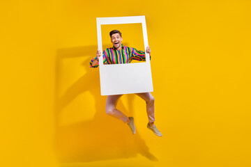 Full length photo of alcoholic guy jump with paper frame zone for instagram blog shooting during...