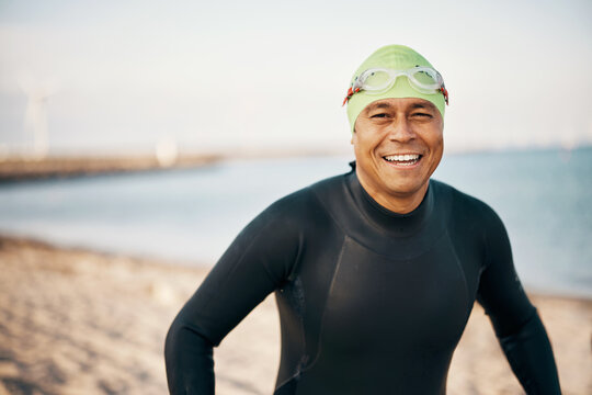 Smiling man wearing a wetsuit and goggles before an open water swim