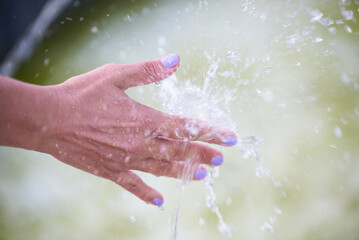 Woman's hand under a stream of water from a fountain