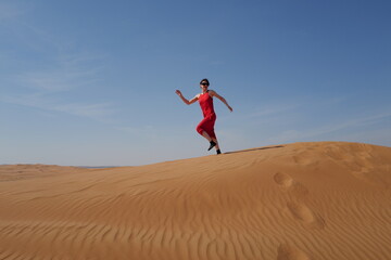 Woman in red dress on sand dunes