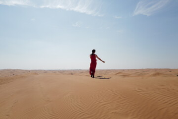 Fototapeta na wymiar Woman in red dress on sand dunes 