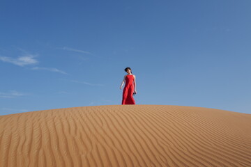 Woman in red dress on sand dunes 