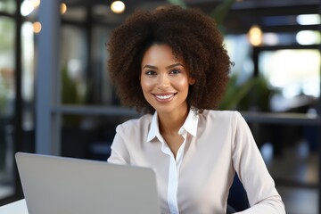 Fototapeta premium Mixed race businesswoman entrepreneur working on a laptop smiling at the camera.