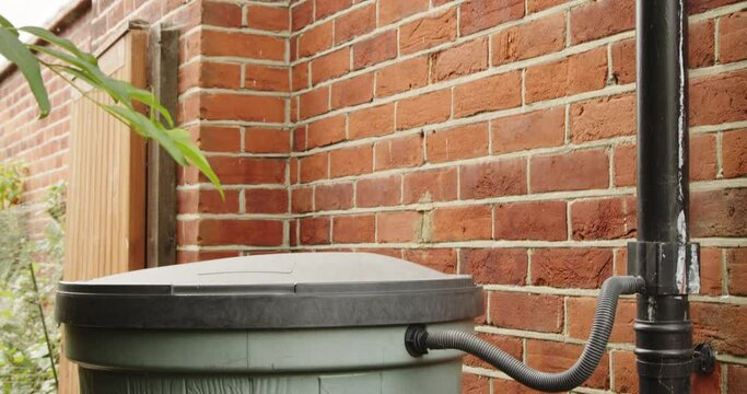 Close-up of a rainwater diverter connecting the roofline drainage pipe to a water storage barrel or garden water storage tank.