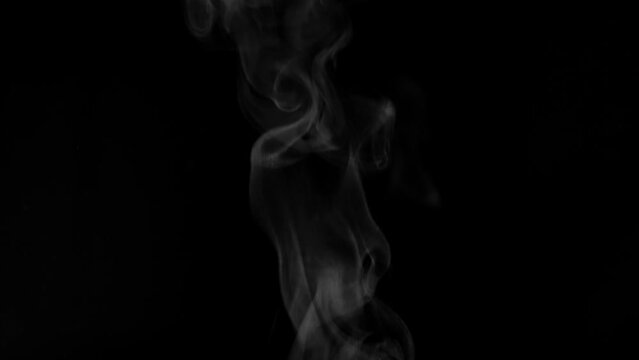 White steam from hot food or drink. White steam on a black background rises to the top. Cooking a hot meal in the kitchen.