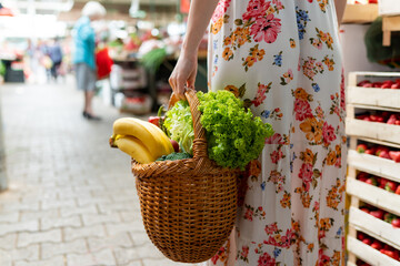 A close-up view of a wooden basket brimming with a variety of fruits and vegetables, showcasing...